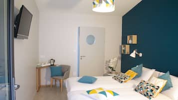 A hotel room with a bed, a desk, a chair, a TV, and a door.