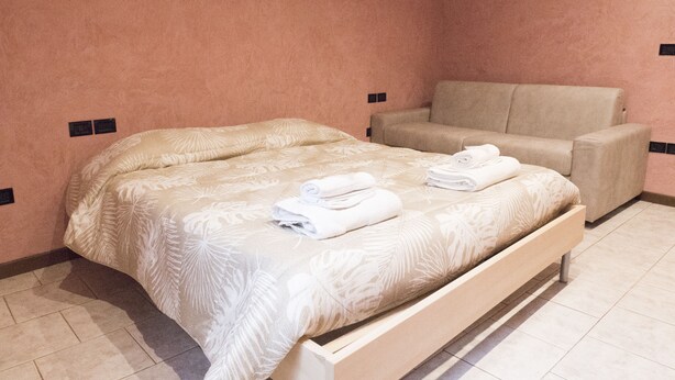 A bedroom with a bed, a sofa, and a small table. - Casa Bella Riva Reno - In the Heart of Bologna (Bologna)