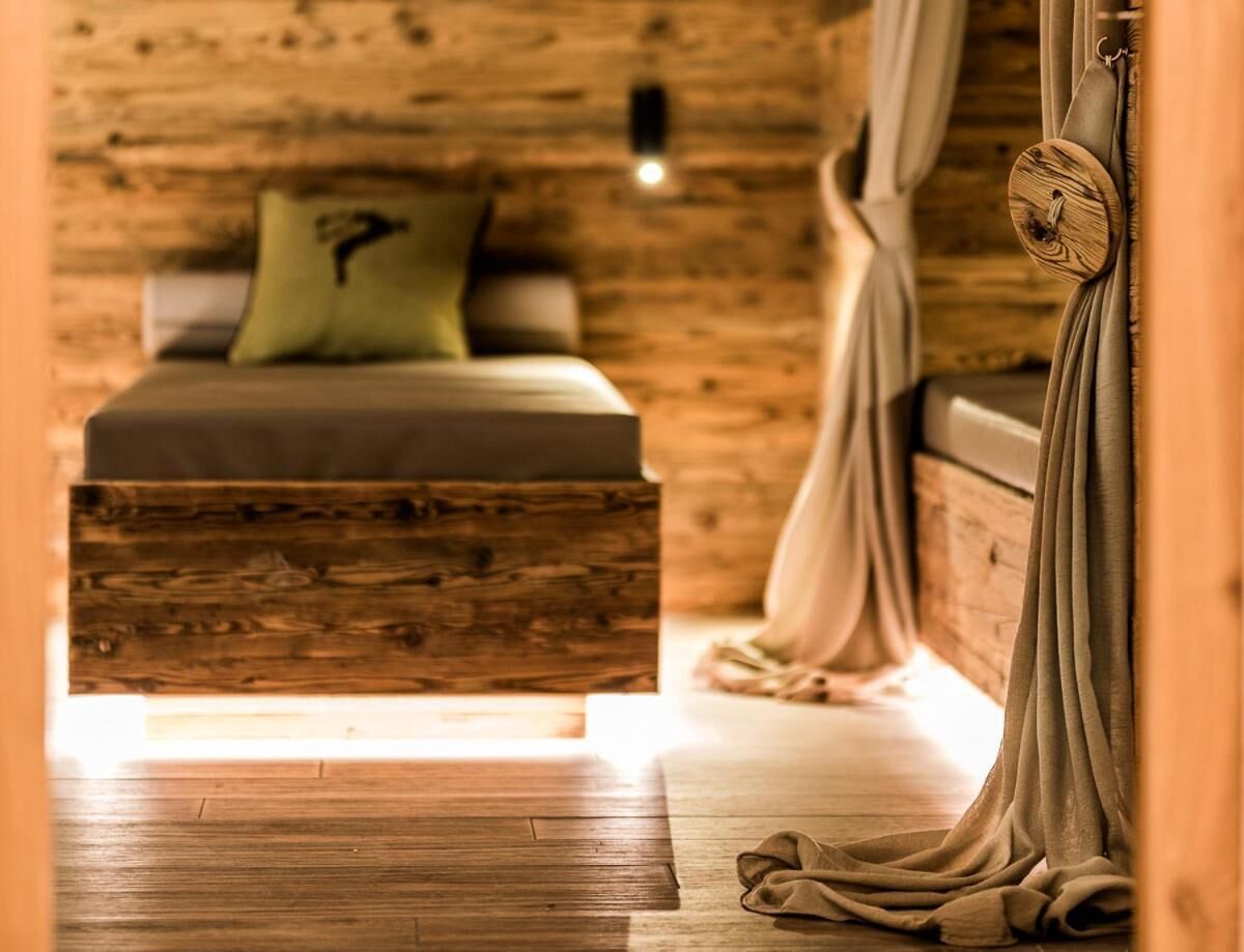 Una habitación rústica de madera con una cama, una silla colgante y una mesita.