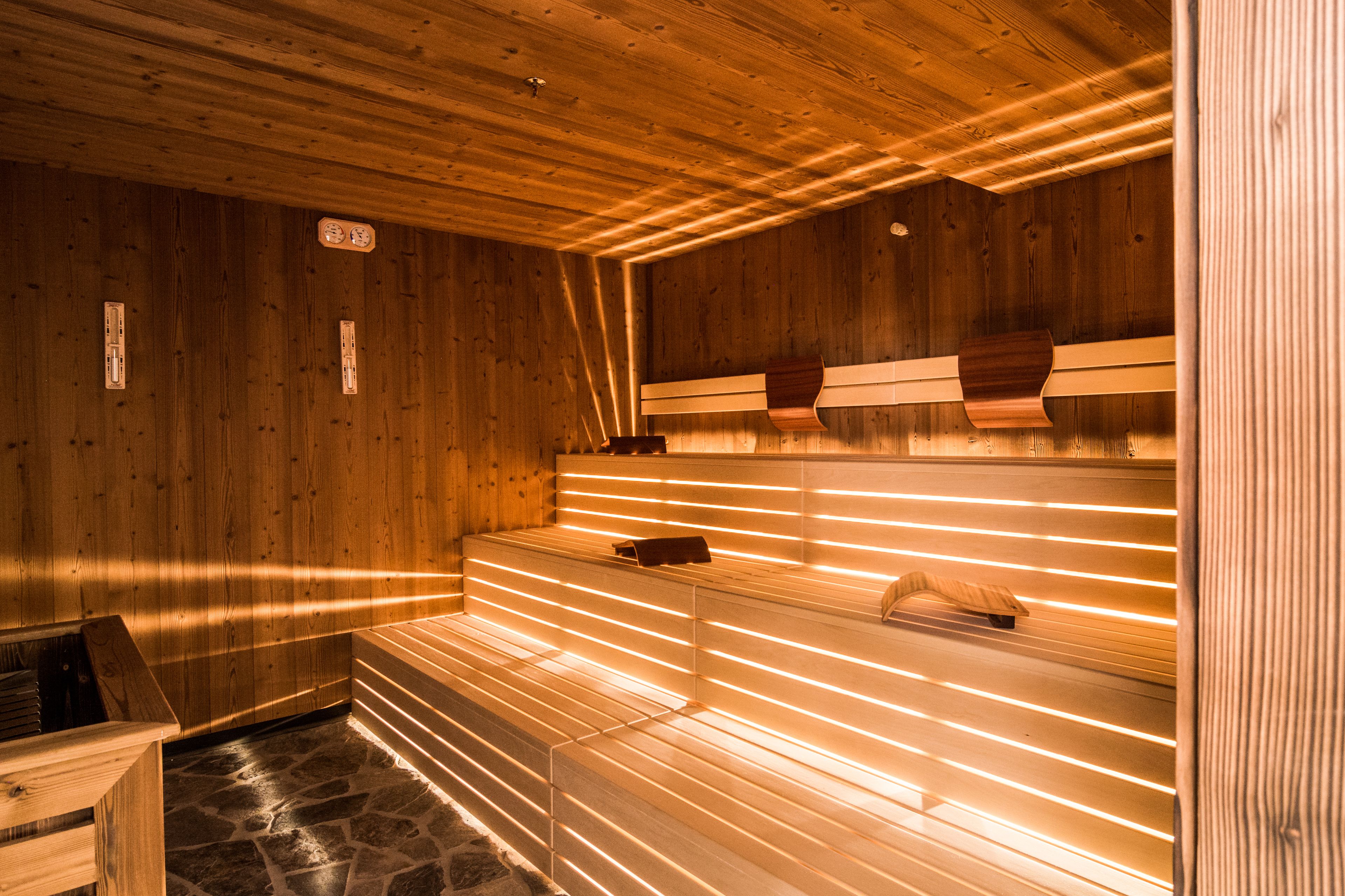 Una sauna con paredes y bancos de madera, suelo de piedra y techo de madera.