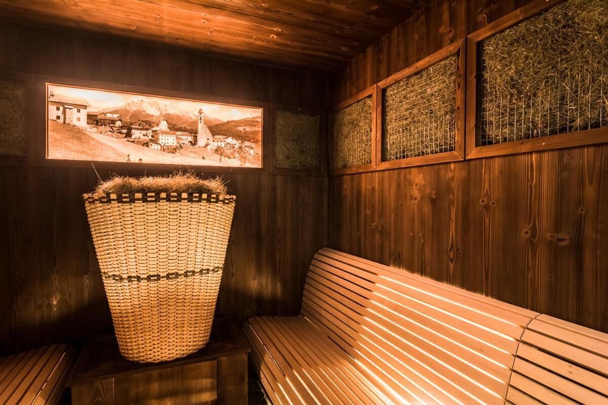 A wooden sauna with a bench, a woven basket, and framed pictures on the wall.