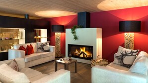 A modern living room with a fireplace, sofas, and a coffee table. - Hotel Regglbergerhof (Nova Ponente)