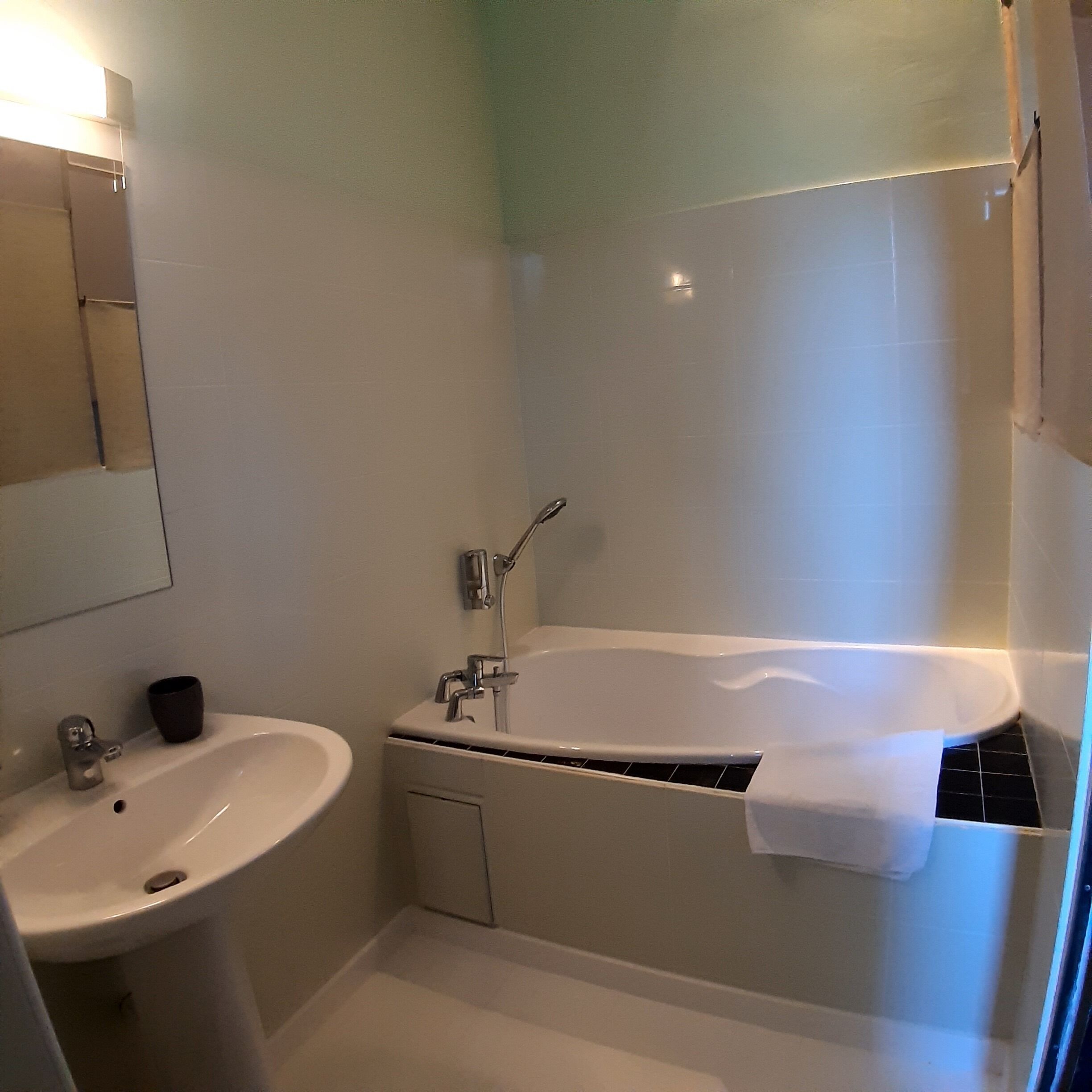 Un bany amb banyera, un lavabo i un mirall.