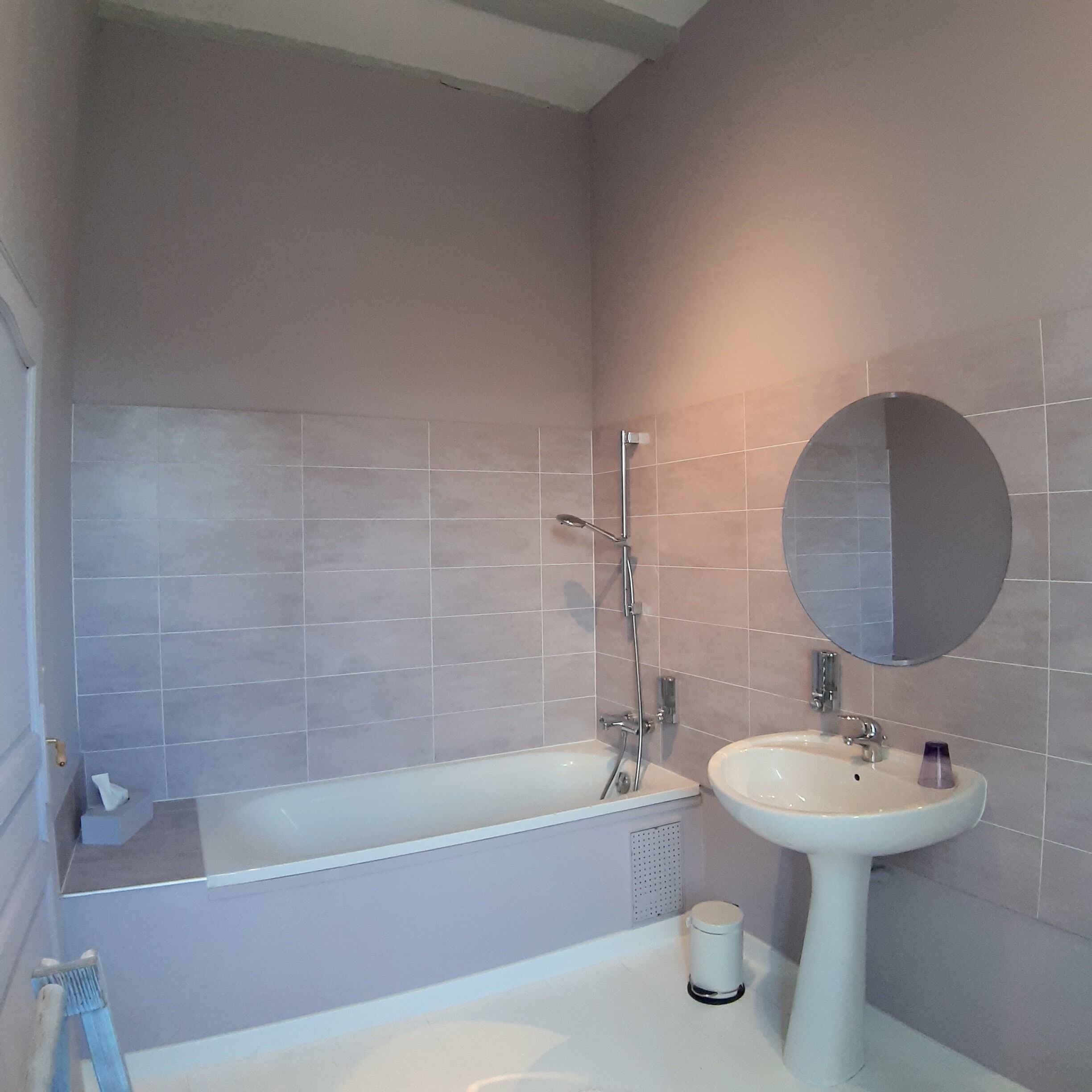 A bathroom with a bathtub, a sink, and a mirror.