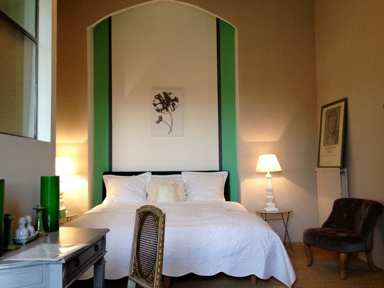 Une chambre d’hôtel comprenant un lit, un bureau, une chaise et une table de chevet avec des lampes.