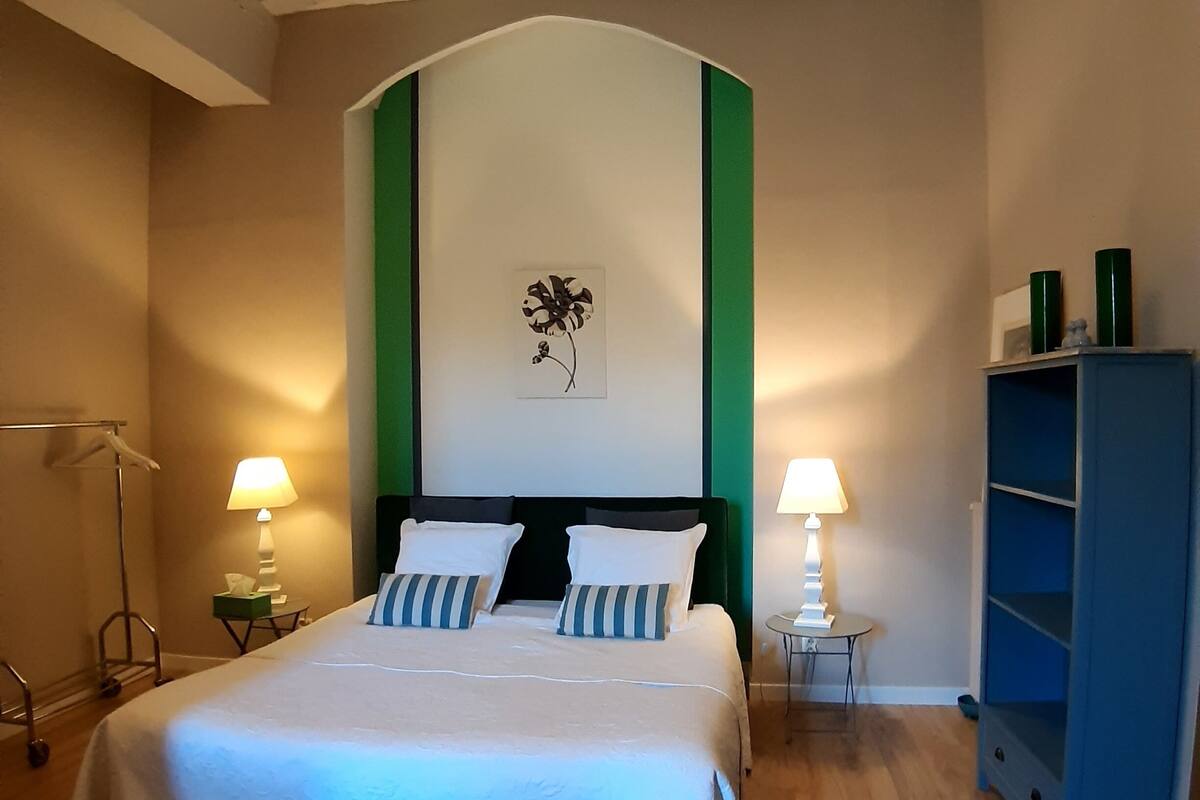 Ein Hotelzimmer mit einem großen Bett, zwei Nachttischen mit Lampen, einer grünen Akzentwand und einem blauen Schrank.
