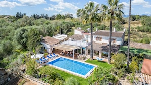 A villa with a swimming pool, outdoor seating, and palm trees. - Sustainable Finca Can Tomeu in Mallorca (Llubi)