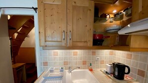 Une cuisine compacte avec des meubles en bois, un évier, une bouilloire et une cuisinière à gaz.
