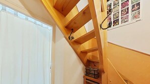 Un escalier en bois avec une rampe métallique, une petite étagère avec un panier et un cadre photo fixé au mur.