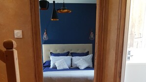 A room with a bed, wooden floor, and a blue wall. - Les Bruyères de Rouen - Seasonal rental (Sotteville-lès-Rouen)