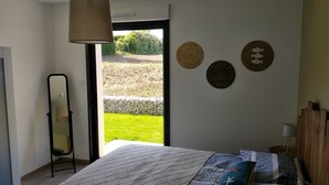 Ein Schlafzimmer mit Bett, Spiegel und Blick auf einen Garten.