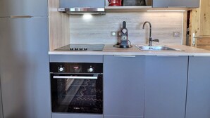 Una cocina compacta con horno Bosch, cafetera y lavamanos.