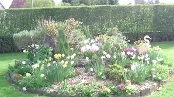 A garden with a variety of flowers and a bird statue.