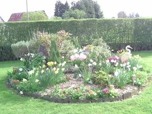 A garden with a variety of flowers and a bird statue. - Chambre d'hotes de la Mousse (Saint-Remy)