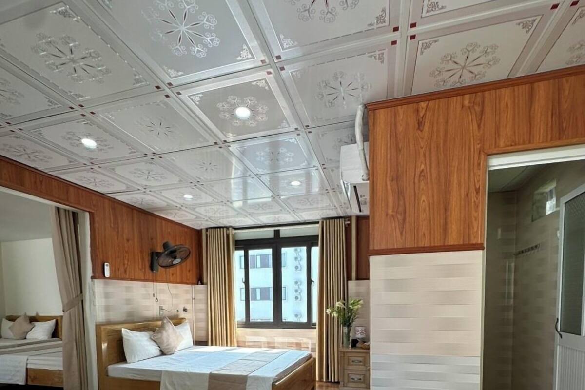 A hotel room with a large bed, a smaller bed, a sitting area, and a bathroom.