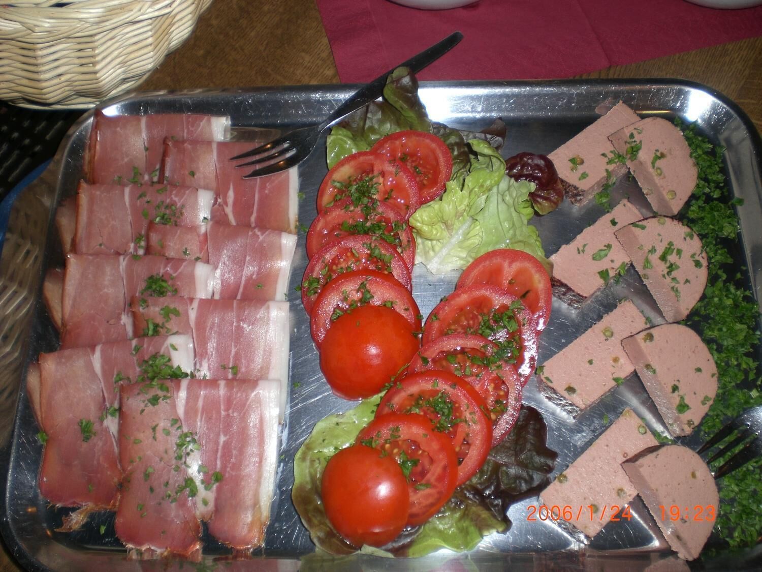 Eine Platte mit Wurstscheiben, Tomaten, Salat und einer Art Pastete.
