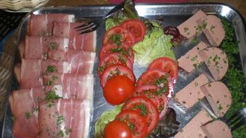 A tray with sliced ham, tomatoes, lettuce, and a type of pâté.