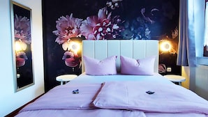A bedroom with a large bed, two bedside tables, and a wall mural of flowers. - Hotel Zur Kupferkanne (Kobern-Gondorf)