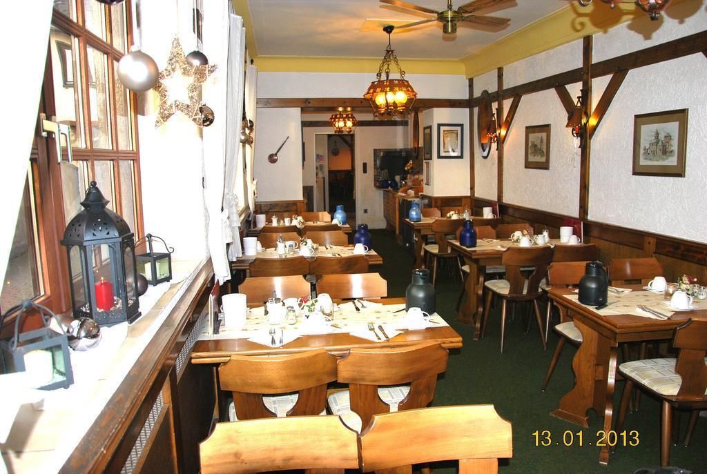 A restaurant with wooden tables and chairs, star-shaped hanging lights, and framed pictures on the walls.