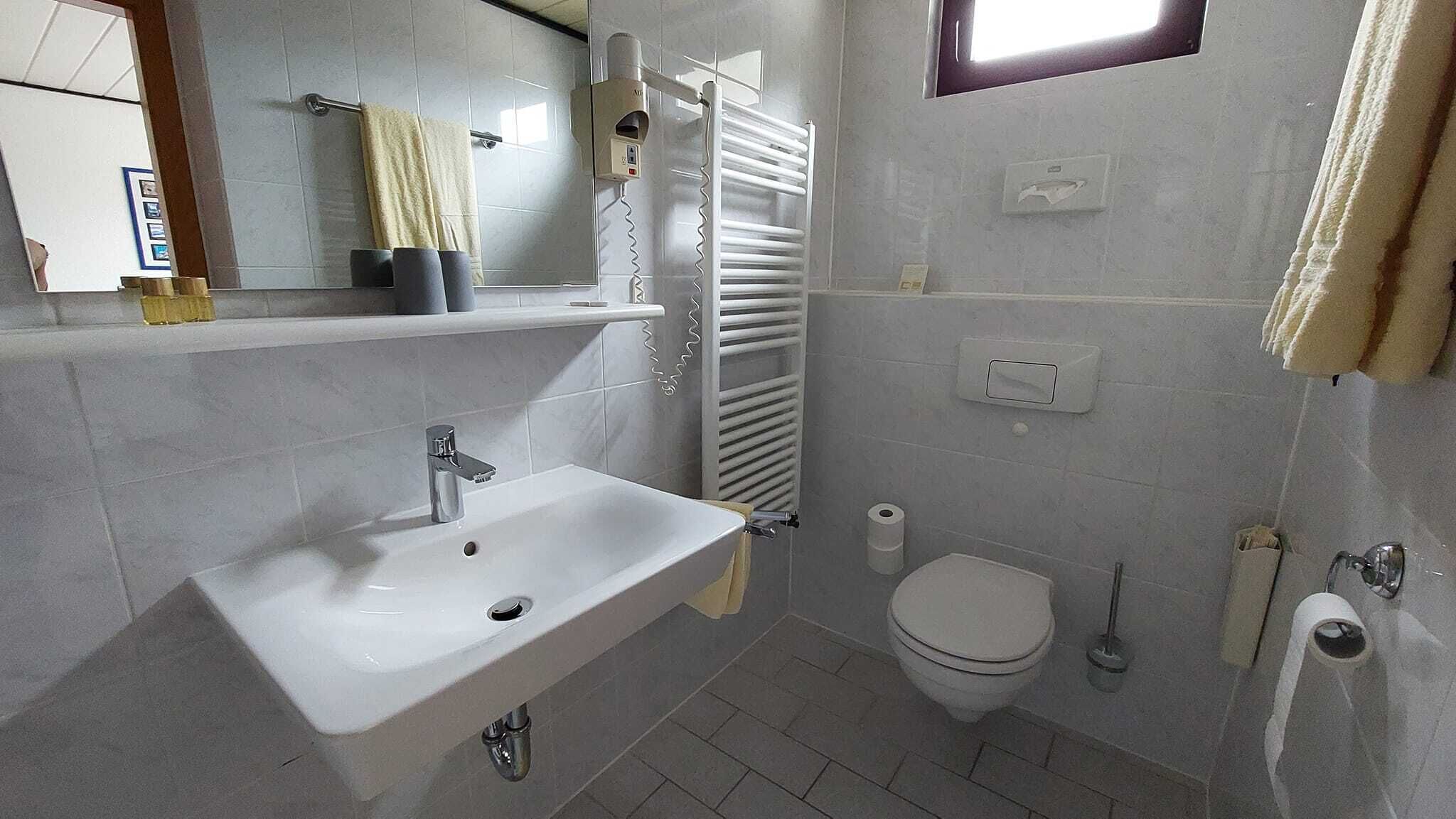 A modern bathroom with a sink, toilet, and towel rack.