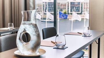 A modern dining table with a unique metallic pitcher centerpiece, a glass, and a menu.