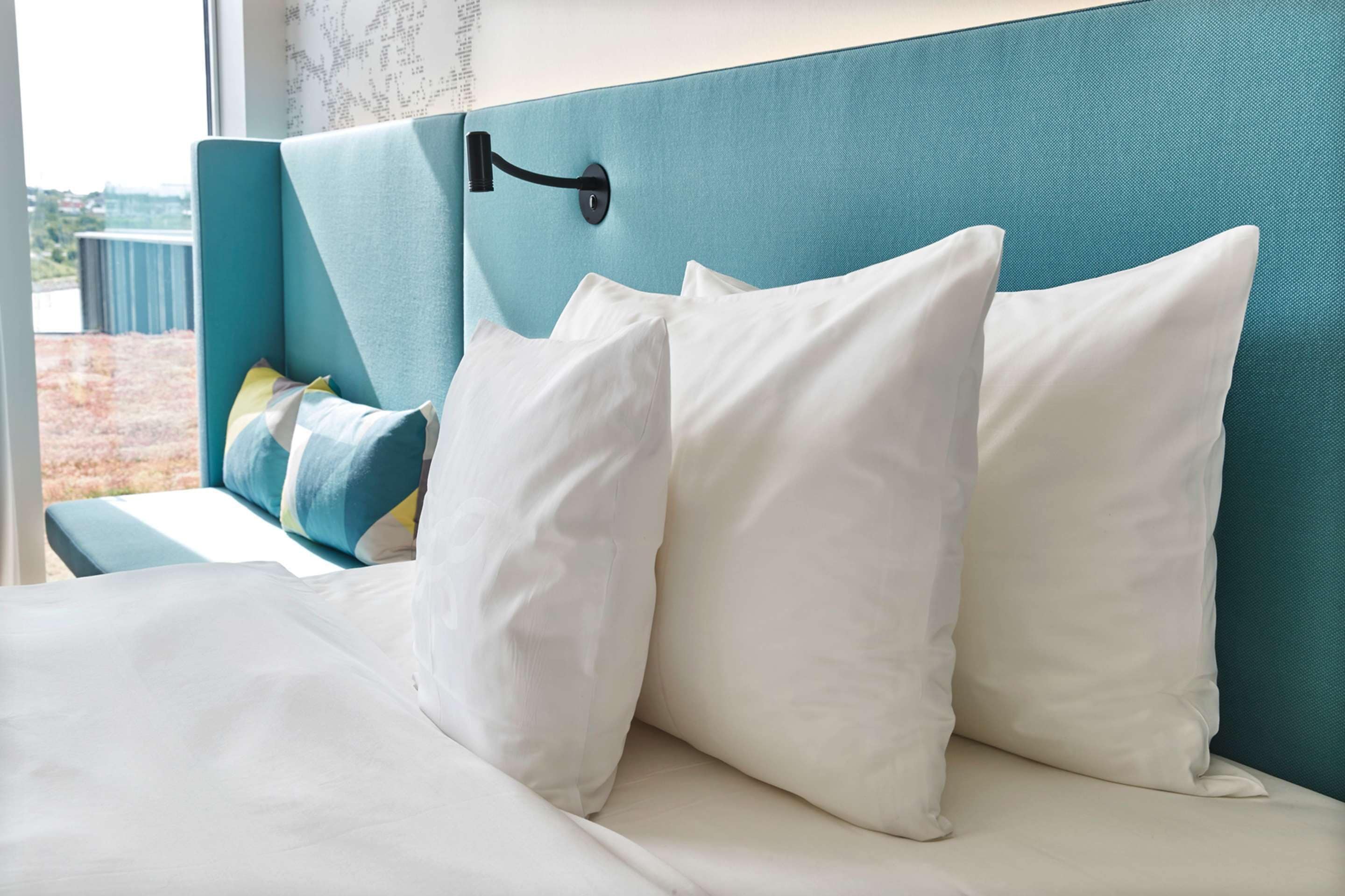 Ein Bett mit weißer Bettwäsche und einem türkisblauen Kopfteil.