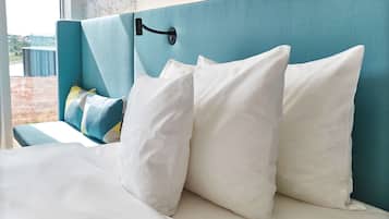 Ein Bett mit weißer Bettwäsche und einem türkisblauen Kopfteil.