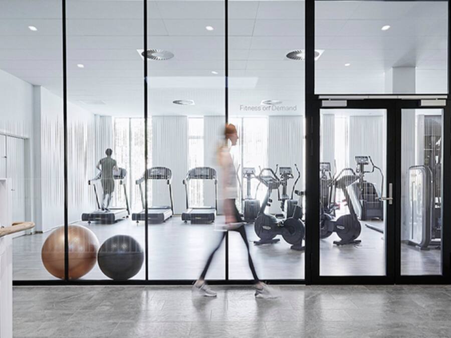 Un gimnasio moderno con máquinas de cardio, pesas libres y un espejo grande.