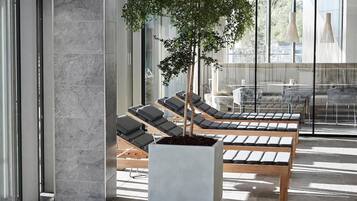 A modern waiting area with lounge chairs and a potted tree.