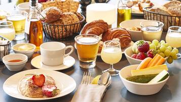 Een ontbijttafel met diverse soorten eten, zoals gebak, fruit en drankjes.