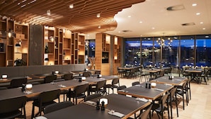Un restaurante moderno con techos de paneles de madera, varias mesas y sillas.