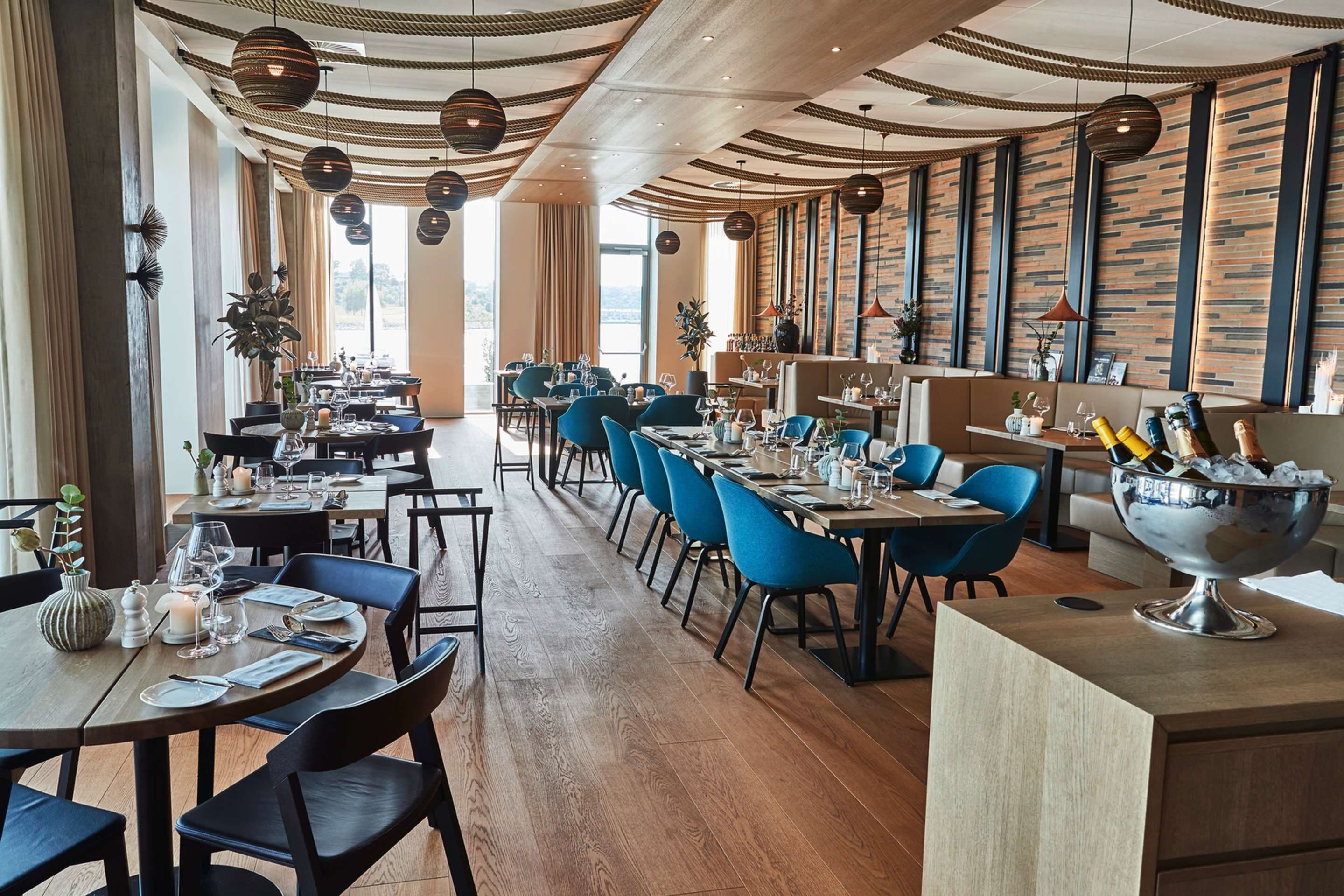 Un restaurante espacioso con techos altos, iluminación moderna y una variedad de opciones de asientos.