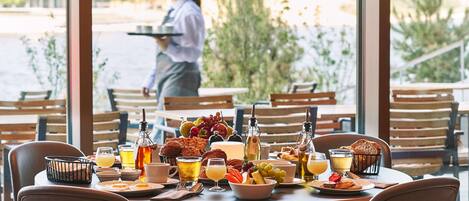 Una mesa de desayuno servida con diversos platos, bebidas y una cesta.