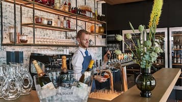 Eine Bar mit Bartender, einem großen Eiseimer mit der Aufschrift "POL ROGER" und einer Blumenvase.