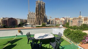A rooftop terrace with a table and chairs, a view of a historic cathedral, and surrounding urban buildings. - Absolute Sagrada Familia (Barcelona)