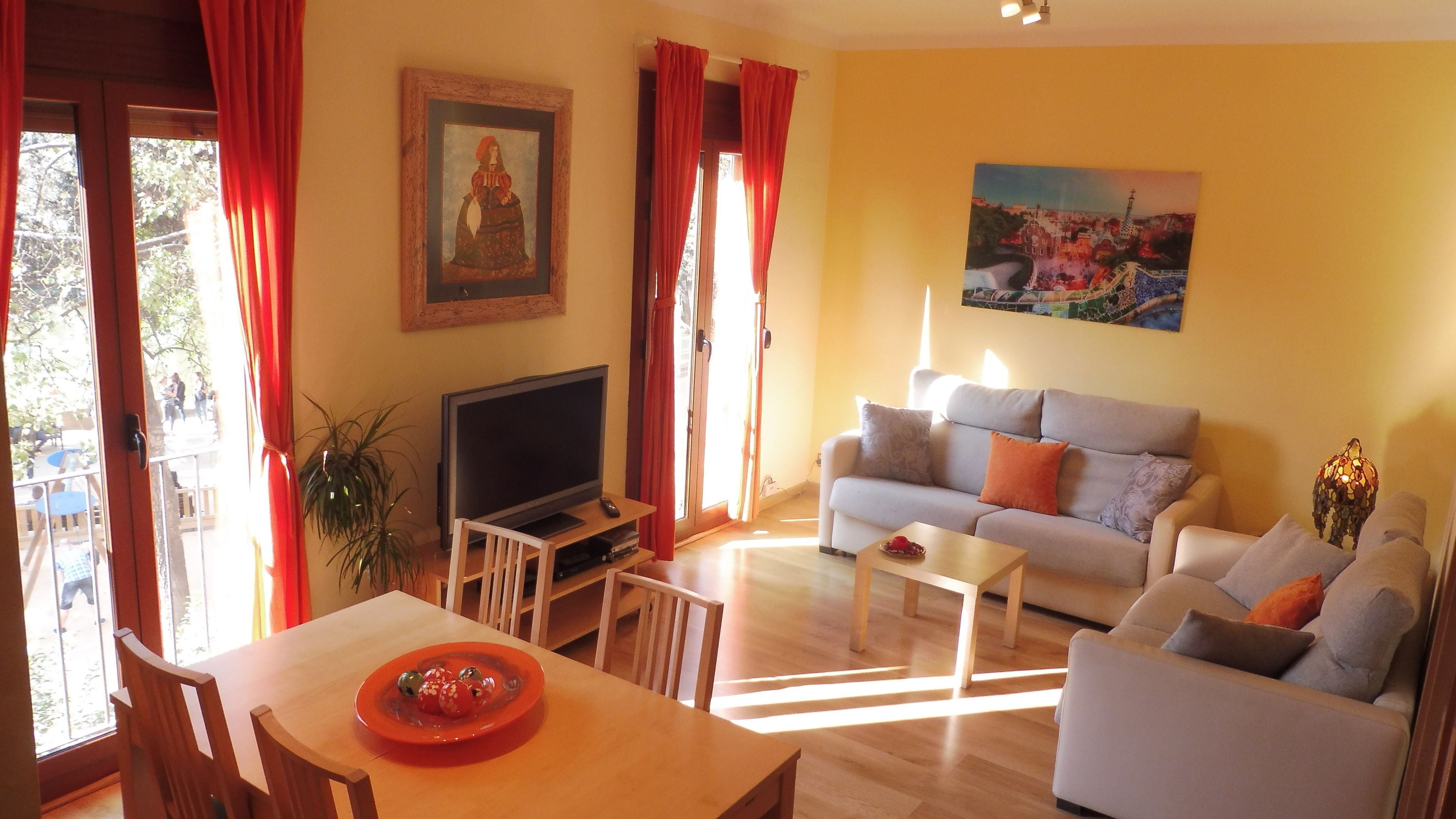 Un salon avec un canapé, un téléviseur, une table sur laquelle se trouve une assiette de fruits et un tableau accroché au mur.