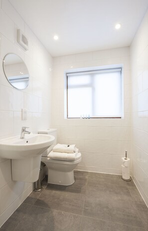 A modern bathroom with a sink, toilet, and window. - High Hedges Apartments (Oxford)