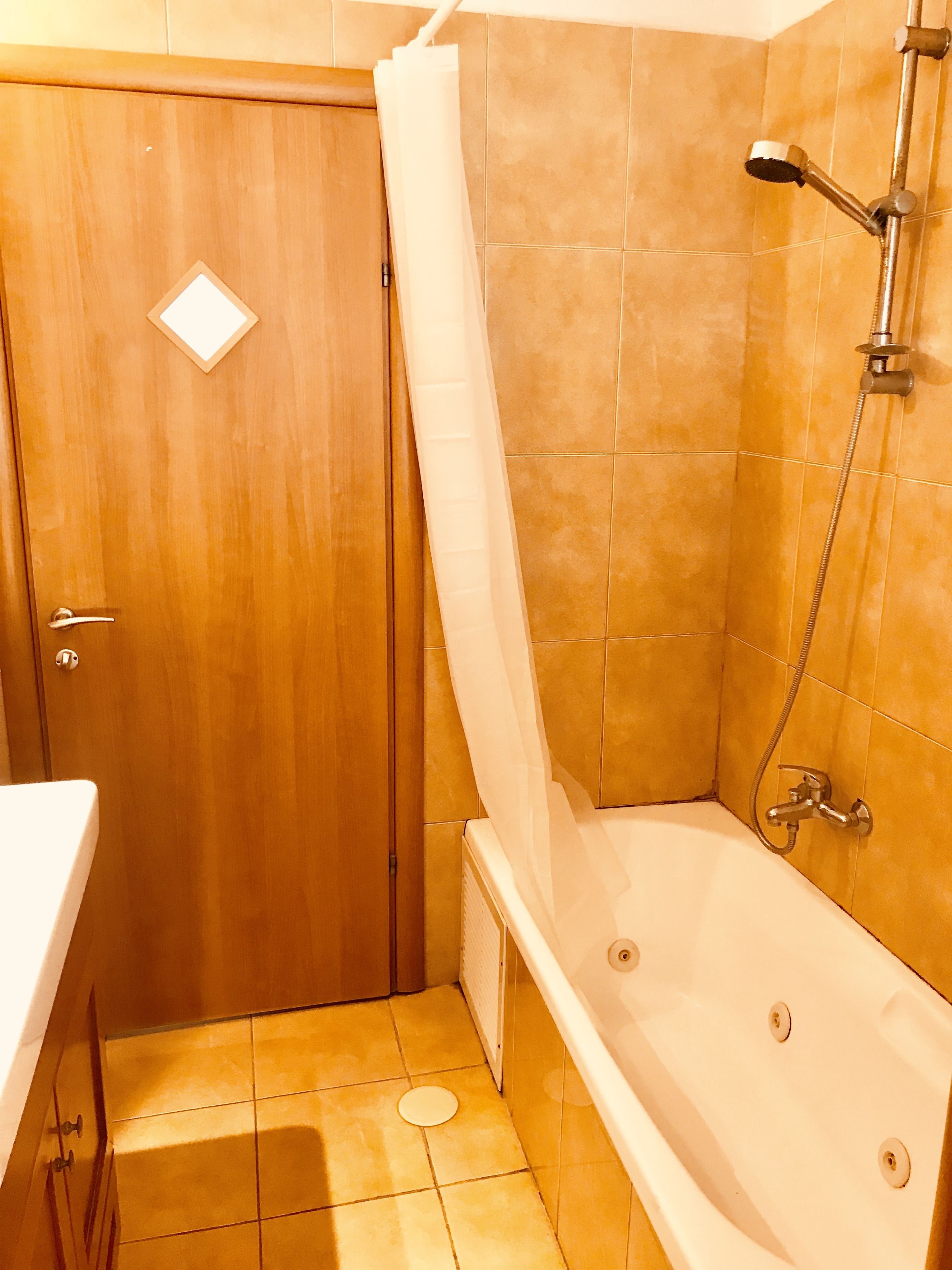 Une salle de bain avec une porte en bois, une douche avec un rideau et une baignoire.