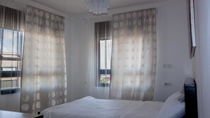 A bedroom with a bed, curtains, a ceiling light, and a window.