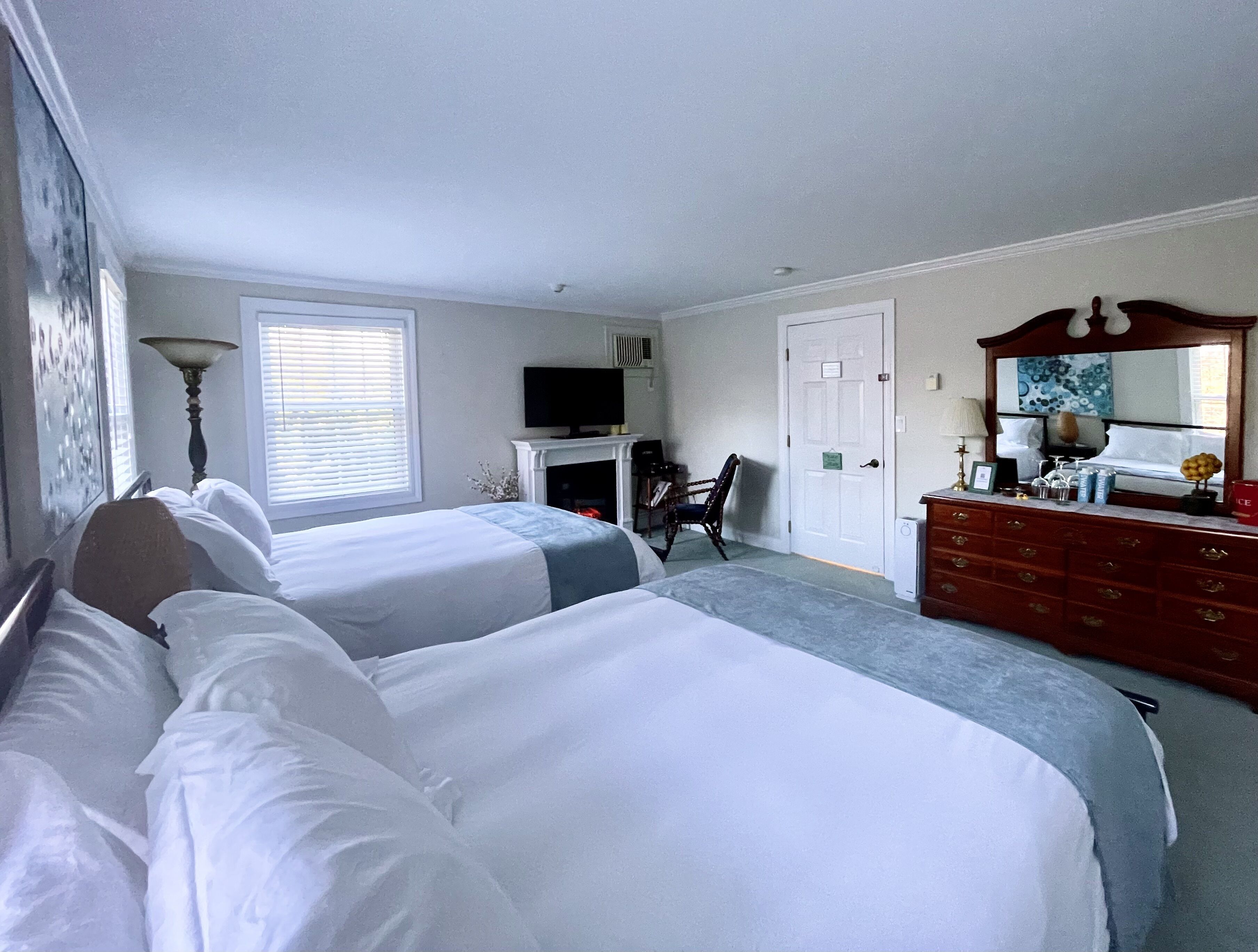 Quarto de hotel com duas camas, televisão, penteadeira e espelho.