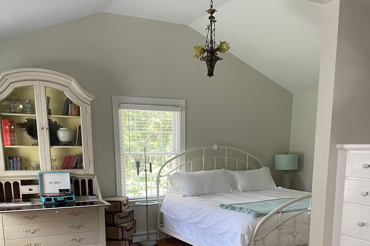 A bedroom with a bed, a dresser, a vanity, and a chandelier.