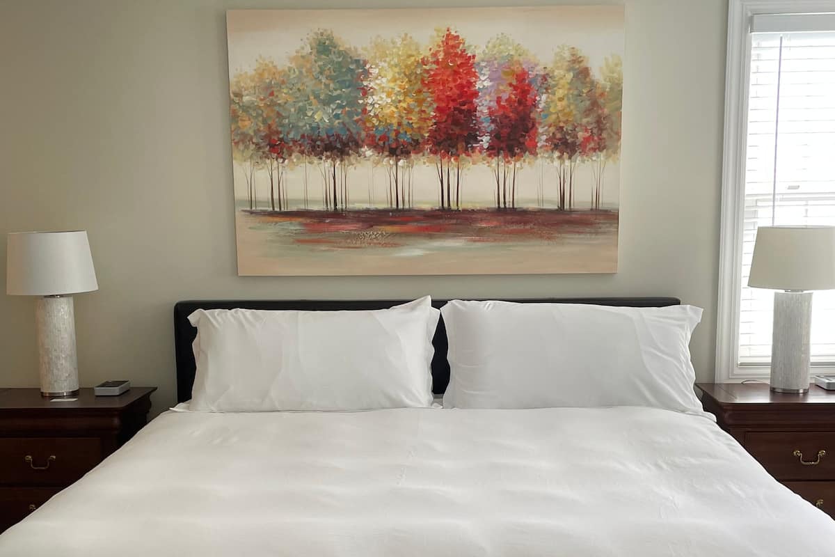 A neatly made bed with white linens in a hotel room.