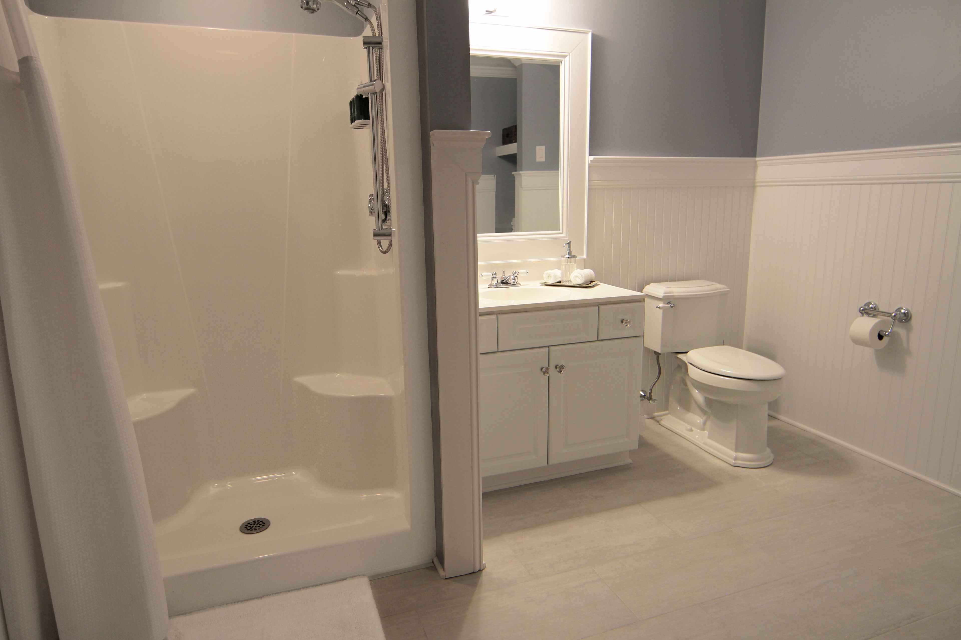 Un bagno con doccia a pavimento, un water e un lavandino.
