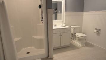 Un bagno con doccia a pavimento, un water e un lavandino.