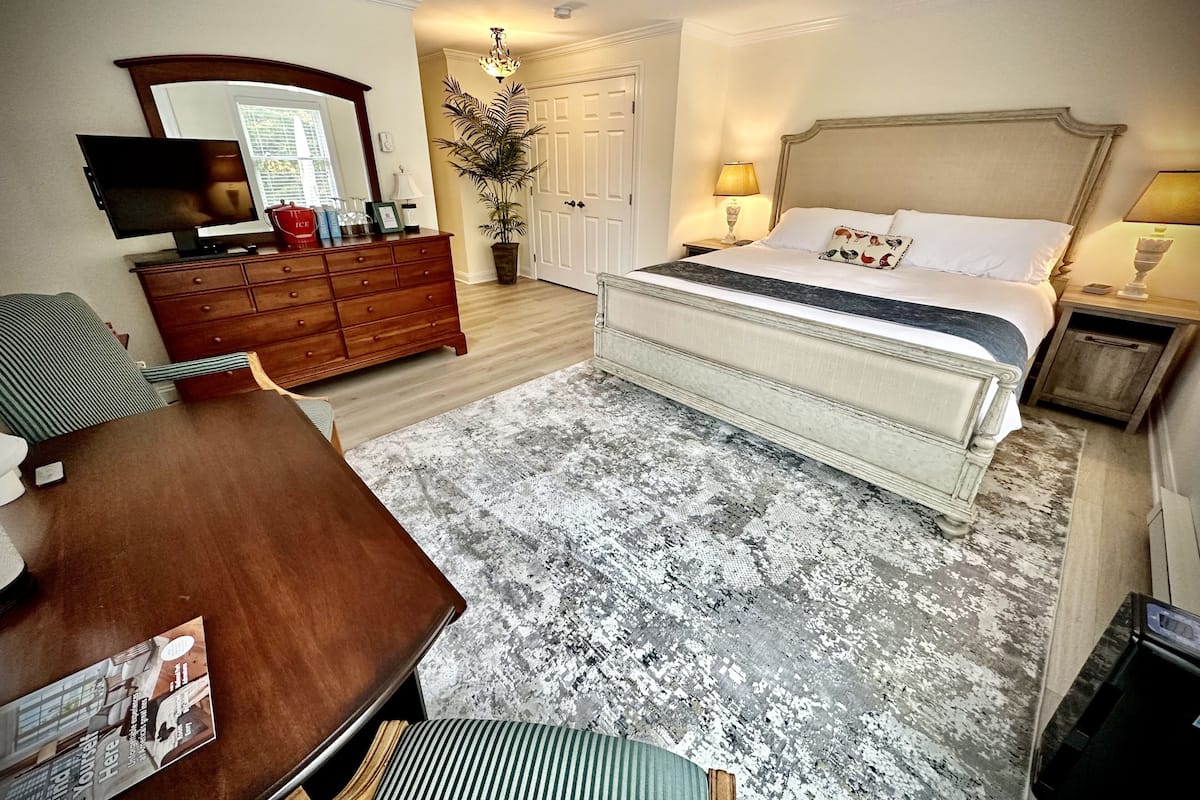 A bedroom with a bed, dresser, and a television on a stand.
