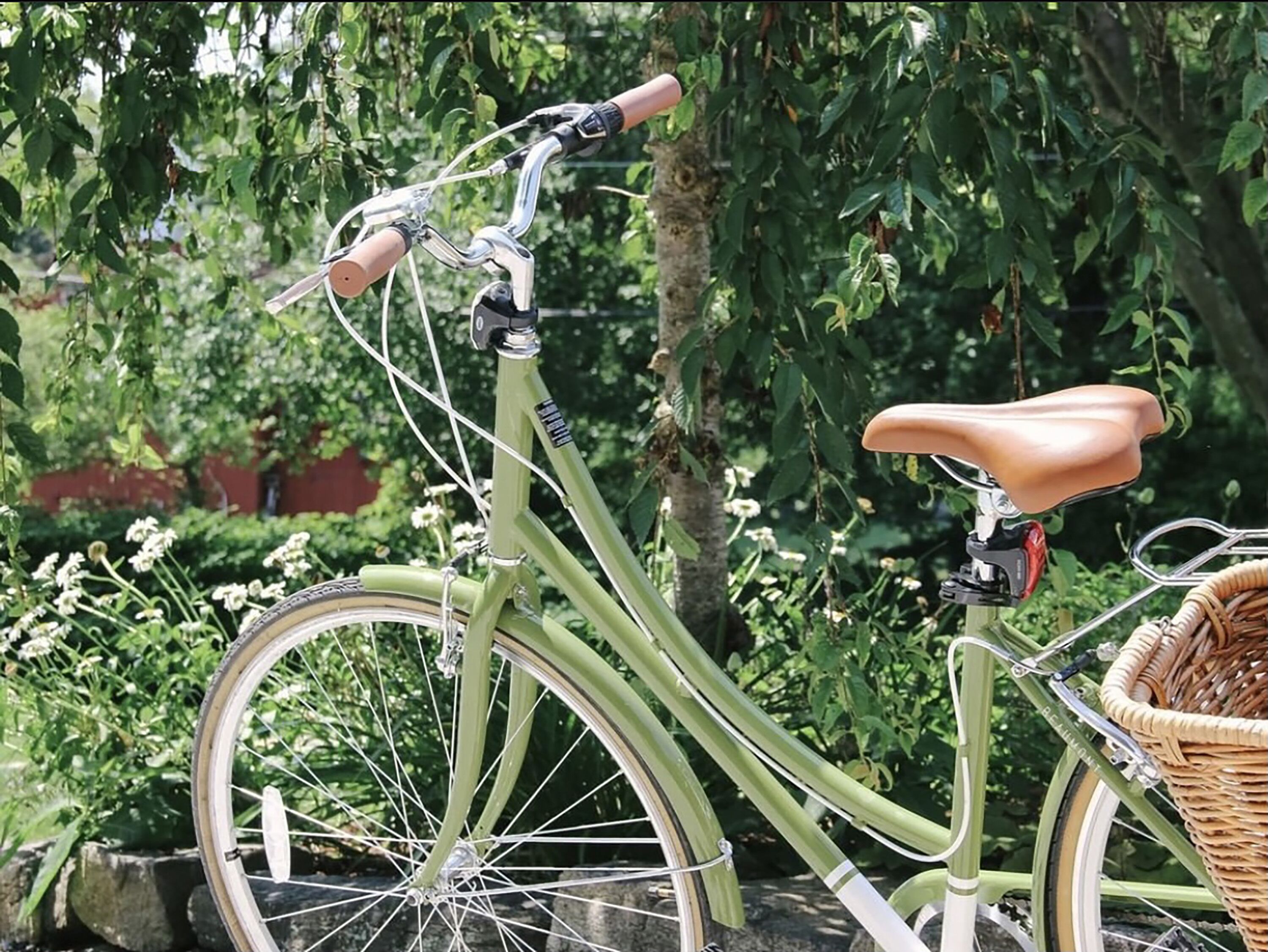 En grön cykel med en korg och en flätkorg som är fastsatt baktill.