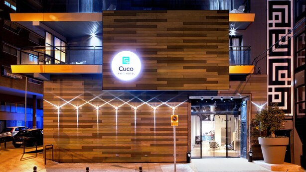 A modern hotel entrance with a wooden facade, a prominent 'Cuco An Inn Hotel' sign, and a no parking sign. - Hotel Cuco (Benidorm)