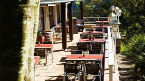 An outdoor patio with tables and chairs, a covered seating area, and a view of the surrounding landscape. - Berghotel Maderhalm (Fischen im Allgaeu)