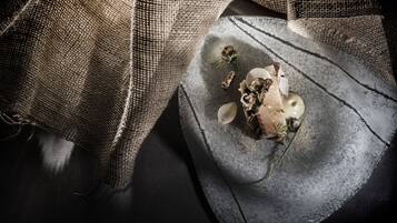 A rustic dining table with a textured cloth, mushrooms, and a sprig of rosemary.