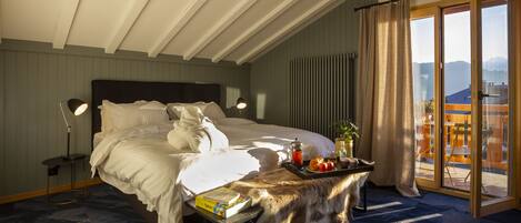 A bedroom with a large bed, a bedside table with a book, a tray with fruits and a drink, and a view of the outdoors through a sliding door.